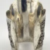Wide peaked silver cuff with three crowned celestial dancers, openwork leafy scrolls and a rounded longevity medallion
