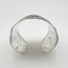 Wide peaked silver cuff with three crowned celestial dancers, openwork leafy scrolls and a rounded longevity medallion
