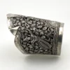 Wide peaked silver cuff with three crowned celestial dancers, openwork leafy scrolls and a rounded longevity medallion