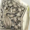Wide peaked silver cuff with three crowned celestial dancers, openwork leafy scrolls and a rounded longevity medallion