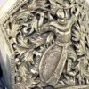 Wide peaked silver cuff with three crowned celestial dancers, openwork leafy scrolls and a rounded longevity medallion