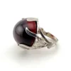 High-domed red glass cabochon ring with broad silver prongs, fleur-de-lis shoulders and an overlapping adjustable band