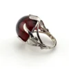 High-domed red glass cabochon ring with broad silver prongs, fleur-de-lis shoulders and an overlapping adjustable band