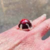 High-domed red glass cabochon ring with broad silver prongs, fleur-de-lis shoulders and an overlapping adjustable band